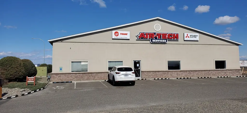 The Air-Tech shop in Pasco, a tan gable with a Trane sign on the left, the Air-Tech Services sign in the middle and a Mitsubishi Electric sign on the right